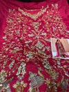 Decorative fabric with gold embroidery on a red background, next to a magazine with a similar design.
