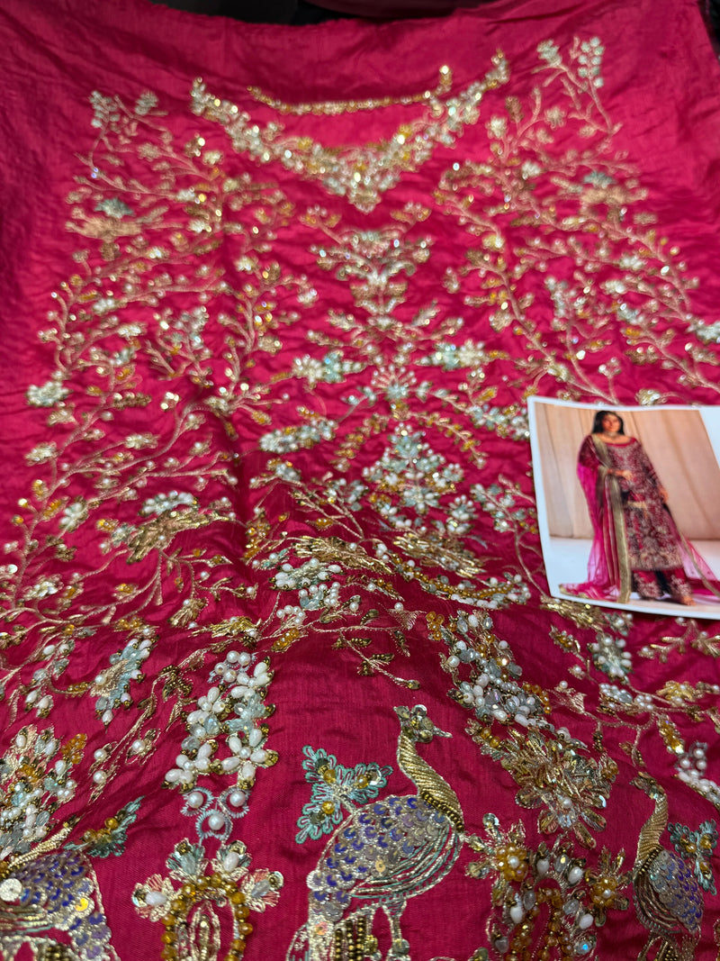 Decorative fabric with gold embroidery on a red background, next to a magazine with a similar design.